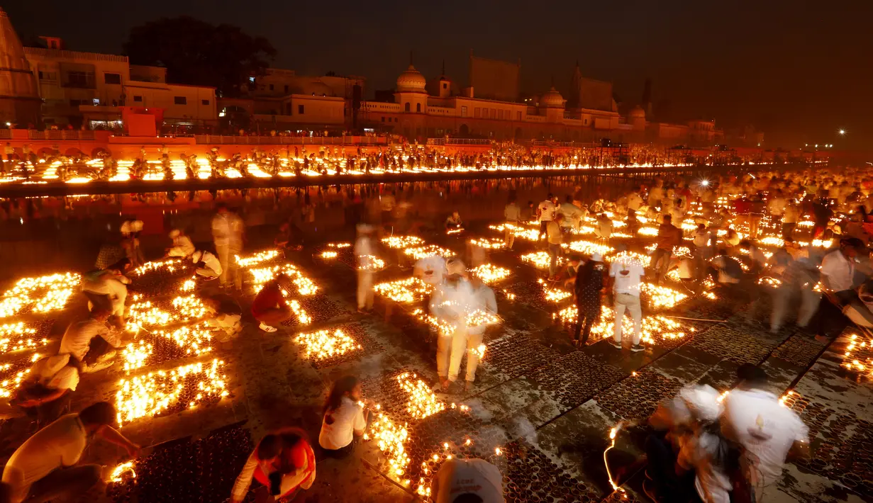Orang-orang menyalakan lampu di tepi sungai Saryu di Ayodhya, India, Rabu (3/11/2021). Lebih dari 900.000 lampu minyak dinyalakan dan terus menyala selama 45 menit saat kota Ayodhya mempertahankan Rekor Dunia Guinness sebagai bagian dari perayaan festival Diwali. (AP Photo/Rajesh Kumar Singh)