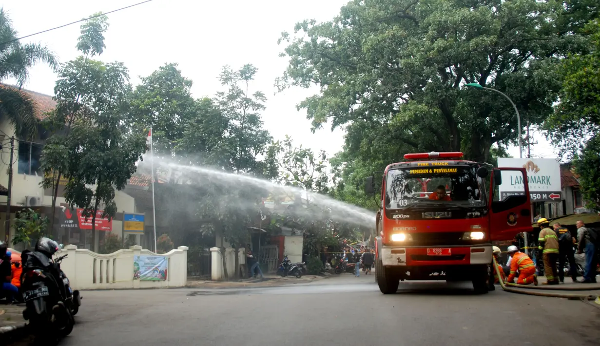 Petugas menerjunkan mobil pemadam kebakaran di luar kantor Kelurahan Arjuna, Kecamatan Cicendo, Bandung, Senin (27/2). Seorang terduga pelaku ledakan bom panci bersembunyi di kantor kelurahan, dan membakar gedung lantai dua. (Timor Matahari/AFP)