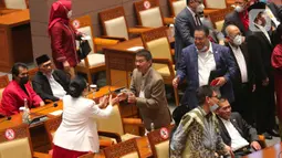 Anggota DPR RI bersalaman sebelum mengikuti pembukaan Rapat Paripurna Pembukaan Masa Persidangan V Tahun Sidang 2021-2022 di Nusantara II, Kompleks Parlemen MPR/DPR-DPD, Senayan, Jakarta, Selasa (17/5/2022). Rapat paripurna hari ini menandakan DPR kembali aktif bersidang setelah selesai menjalani masa reses. Hadir 76 anggota yang secara fisik, 252 secara virtual dan izin 5 anggota. Sehingga total kehadiran rapat paripurna hari ini adalah 333 dari 575 anggota DPR. (Liputan6.com/Angga Yuniar)