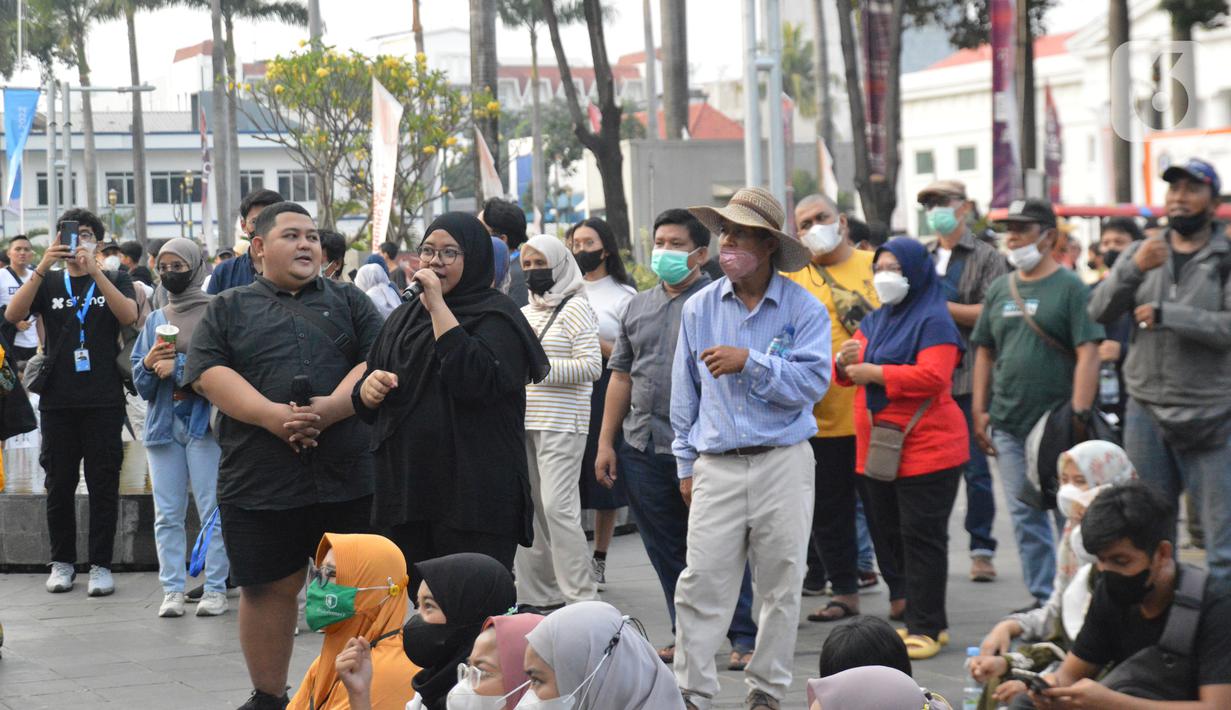 Dua orang penerjemah bahasa isyarat yang sedang memegang mic dan berpakaian serba hitam pada Sesi NGOBAR TULI (Ngobrolbareng Tuli) di Festival #IniJakarta2022, Kota Tua, Jakarta, Minggu (18/9/2022). Seorang penerjemah bahasa isyarat harus mengenakanpakaianberwarna hitam polos atau biru gelap saat bertugas dan tidak memakai perhiasan atau aksesori yang dapat mengalihkan perhatian teman tuli saat menerjemahkan bahasa isyarat.(Liputan6.com/Magang/Aida Nuralifa)