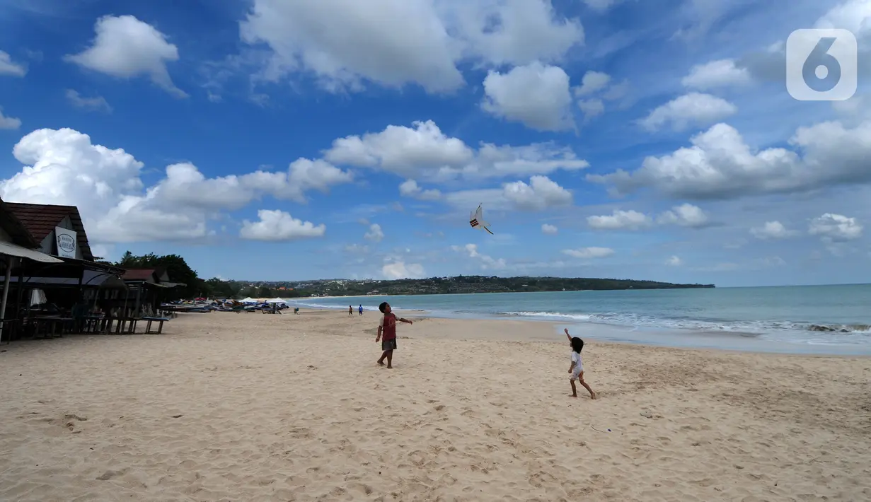 Anak-anak bermain layang-layang di kawasan Pantai Jimbaran, Bali, Jumat (3/9/2021). Sepinya wisatawan yang datang ke Pulau Bali selama PPKM Darurat yakni hanya sebesar rata-rata 500 wisatawan lokal menyebabkan sejumlah tempat wisata pantai sepi pengunjung. (merdeka.com/Arie Basuki)
