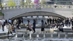 Orang-orang yang memakai masker menyeberangi Sungai Cheonggye di Seoul, Korea Selatan, Jumat (15/4/2022). Korea Selatan atau Korsel akan menghapus sebagian besar pembatasan pandemi covid-19, termasuk batas berkumpul di dalam ruangan, mulai 18 April 2022. (AP Photo/Ahn Young-joon)
