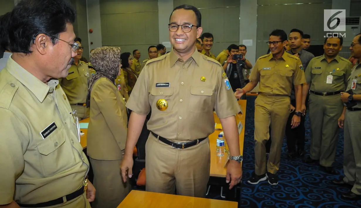 Gubernur dan Wakil Gubernur baru DKI, Anies Baswedan dan Sandiaga Uno bersiap menggelar rapat dengan jajaran pejabat Pemprov DKI Jakarta di Balai Kota, Selasa(17/10). Anies-Sandi tampak necis mengenakan pakaian dinas PNS. (Liputan6.com/Faizal Fanani)