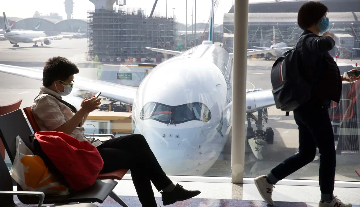 Para pelancong yang mengenakan masker menunggu penerbangan mereka di Bandara Internasional Hong Kong di Hong Kong, Selasa (21/1/2020). Masker terjual habis dan pemeriksaan suhu di bandara dan stasiun kereta api menjadi norma baru di China menyusul merebaknya wabah virus corona.  (AP/Ng Han Guan)