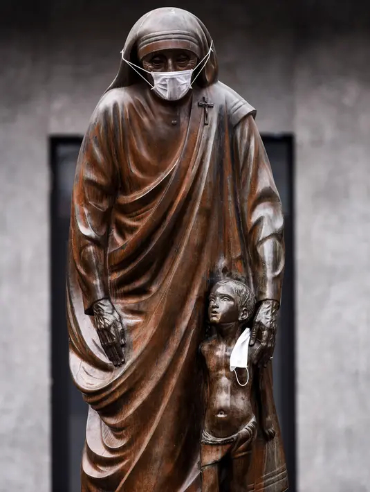 Masker terpasang pada wajah patung Bunda Teresa di Pristina, Kosovo, Kamis (19/12/2019). Pristina dan beberapa kota di Kosovo mengalami polusi udara tingkat tinggi. (Armend NIMANI/AFP)