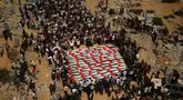 Warga Palestina berkumpul di sekitar jenazah warga Palestina yang tewas dalam serangan Israel selama perang dengan Hamas setelah ditemukan dari bawah reruntuhan bangunan, dalam prosesi pemakaman di Kota Gaza, Kamis (1/10/2026). Jenazah yang ditutupi bendera Palestina tersebut diiringi keluarga dan warga dalam suasana duka. (AP Photo/Yousef Al Zanoun)