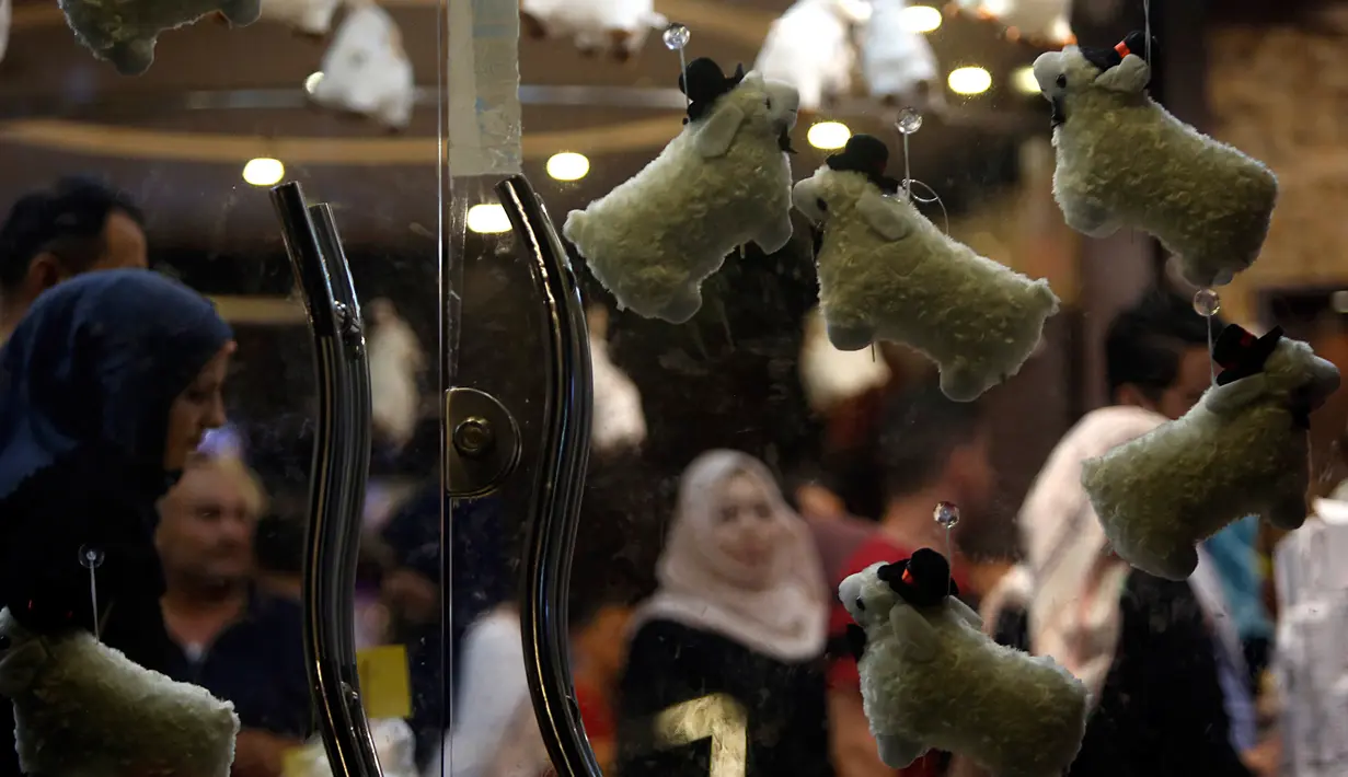 Keluarga Palestina membeli cokelat di sebuah toko yang dihiasi dengan boneka domba menjelang Hari Raya Idul Adha di kota Gaza pada Rabu (29/7/2020). (AP Photo/Hatem Moussa)