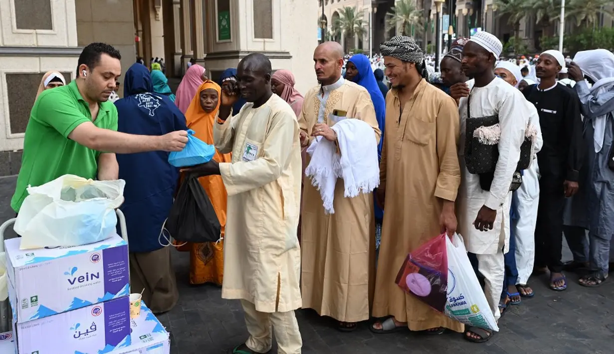 <p>Seorang sukarelawan membagikan paket makanan yang ditawarkan oleh penduduk Makkah kepada para jemaah haji di Kota Suci Makkah, Arab Saudi, 23 Juni 2023. (Sajjad HUSSAIN/AFP)</p>