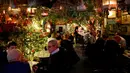 Pelanggan berbincang di bar The Churchill Arms dengan dekorasi Natal, London, Inggris, 20 Desember 2016. Menyambut Natal, bagian luar bangunan bar tersebut ditutupi lebih dari 80 pohon natal dan hampir 22.000 lampu berkelap-kelip. (REUTERS/Neil Hall)