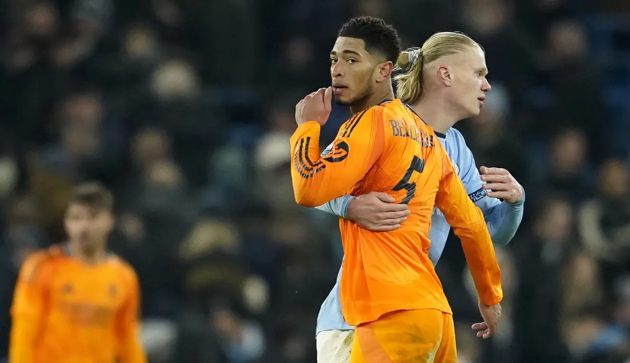 Pemain Real Madrid, Jude Bellingham berpelukan dengan pemain Manchester City, Erling Haaland dalam laga leg 1 babak playoff Liga Champions 2024/2025 di Etihad Stadium, Manchester, Inggris, Rabu (12/02/2025) WIB. (AP Photo/Dave Thompson)