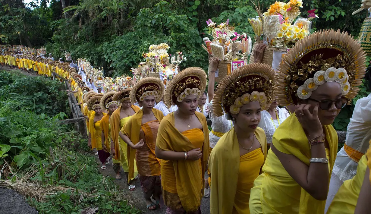 Para wanita yang mengenakan pakaian adat berbaris saat berjalan dalam ritual Hindu Bali bernama Usaba Sri di Karangasem, Bali, Senin, 10 Agustus 2026. (Foto AP/Firdia Lisnawati)
