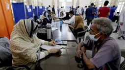 Petugas kesehatan mengumpulkan informasi dari orang-orang sebelum melakukan vaksin virus Corona Sinopharm, di pusat vaksinasi, di Karachi, Pakistan, Rabu (10/3/2021). Pakistan telah mulai memvaksinasi orang yang berusia 60 tahun ke atas untuk melindungi mereka dari COVID-19 (AP Photo/Fareed Khan)