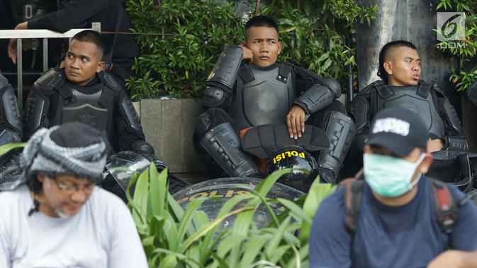 Personil kepolisian dari satuan Brimob beristirahat saat menjaga aksi unjuk rasa yang dilakukan Gerakan Nasional Kedaulatan Rakyat di depan Gedung Bawaslu, Jakarta, Selasa (21/5/2019). Ribuan aparat keamanan gabungan diterjunkan untuk mengamankan jalannya aksi. (Liputan6.com/Helmi Fithriansyah)