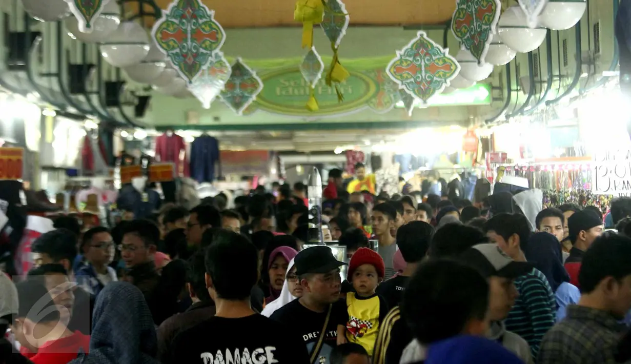 Seorang ayah sambil menggendong anaknya mengunjungi salah satu pusat perbelanjaan di kawasan Blok M, Jakarta, Selasa (14/7). Menjelang Idul Fitri 1436, transaksi penjualan di sejumlah pusat perbelanjaan mengalami peningkatan. (Liputan6.com/Helmi Afandi)
