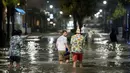 Orang-orang berjalan melalui genangan air di Ocean Boulevard di Pantai Myrtle, Carolina Selatan (3/8/2020). Badai Isaias terus bergerak ke utara di sepanjang pesisir timur AS. (Sean Rayford/Getty Images/AFP)