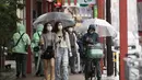 Dua wanita memakai masker wajah untuk mengekang penyebaran virus corona berjalan di area perbelanjaan Asakusa saat hujan turun di Tokyo (28/5/2021). Infeksi virus corona di Jepang masih belum melambat saat bersiap untuk menjadi tuan rumah Olimpiade hanya dalam waktu 50 hari. (AP Photo/Hiro Komae)