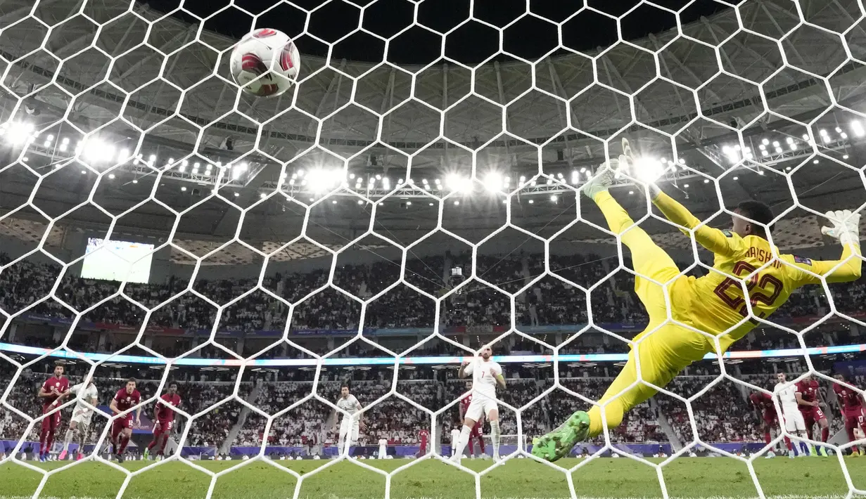 Kiper Iran, Meshaal Barsham gagal menghalau bola tendangan penalti pemain Iran, Alireza Jahan Bakhsh pada laga semifinal Piala Asia 2023 di Al Thumama Stadium, Doha, Qatar, Rabu (07/02/2024). (AFP/Aijaz Rahi)