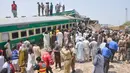 Tim penyelamat dan penduduk setempat berkumpul di dekat kecelakaan dua kereta di distrik Rahim Yar Khan, Pakistan, Kamis (11/7/2019). Kecelakaan terjadi ketika kereta penumpang yang melaju dari arah timur kota Lahore menabrak kereta barang yang berhenti di persimpangan. (AP Photo/Waleed Saddique)