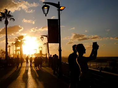 Orang-orang mengambil gambar terjangan ombak saat matahari terbenam di sepanjang garis pantai Beirut, Lebanon (26/10).  (AP Photo / Hassan Ammar)
