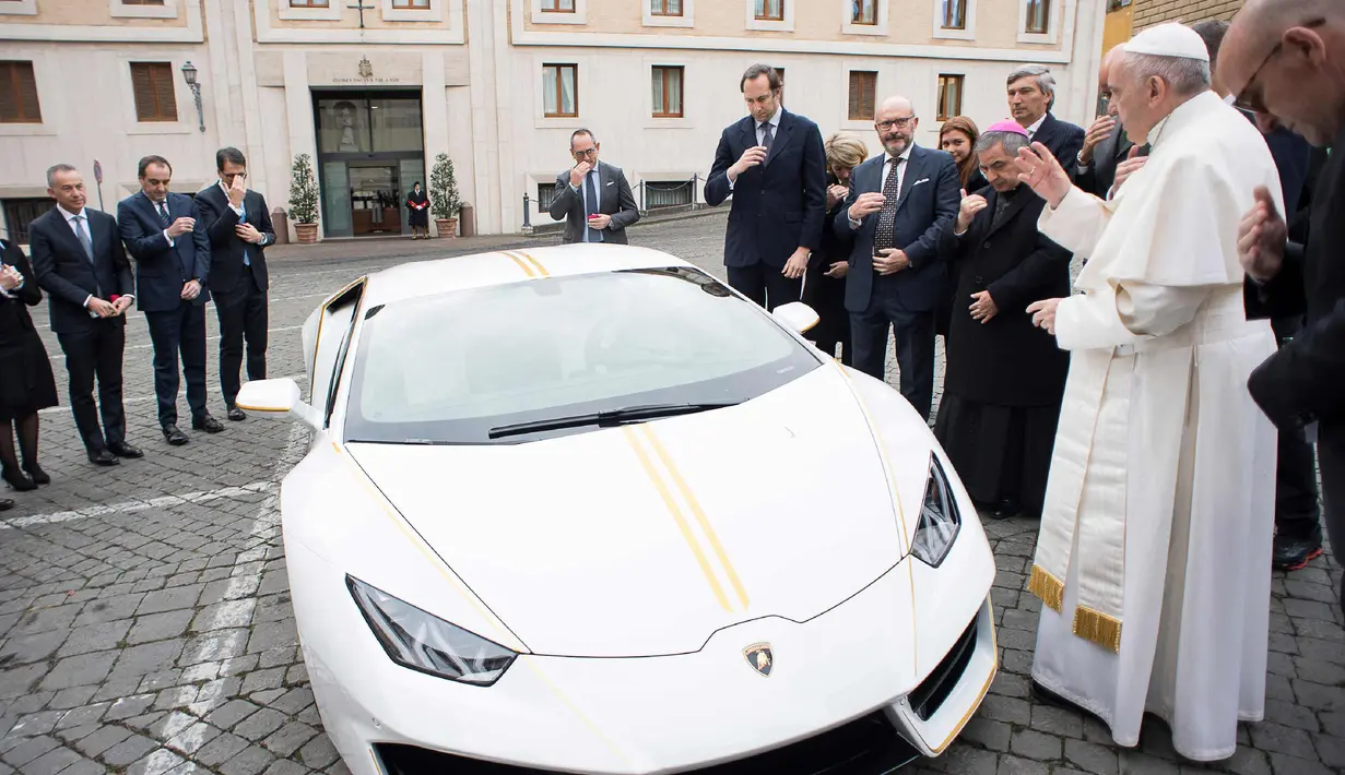 Paus Fransiskus saat menerima hadiah mobil Lamborghini Huracan di Vatikan, Rabu (15/11). Mobil Lamborghini ini oleh Paus rencananya akan dilelang dan hasilnya akan digunakan untuk membantu jemaah Kristen di Irak. (L'Osservatore Romano/Pool Photo via AP)