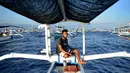Seorang pria mengemudikan perahu saat wisata melihat lumba-lumba di perairan Pantai Lovina di Singaraja, Bali, Jumat (30/10/2020). Pantai Lovina menjadi salah satu destinasi pariwisata di Bali yang sering dikunjungi untuk menikmati matahari terbit dan lumba-lumba di laut lepas (SONNY TUMBELAKA/AFP)