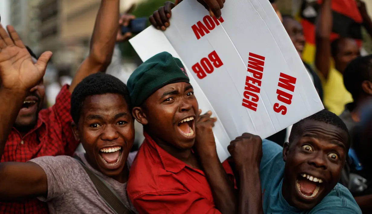 Warga Zimbabwe bergembira setelah kabar Presiden Robert Mugabe mengundurkan diri di luar gedung parlemen, pusat kota Harare, Selasa (21/11). Surat pengunduran diri Robert Mugabe itu mengakhiri masa pemerintahannya selama 37 tahun. (AP/Ben Curtis)
