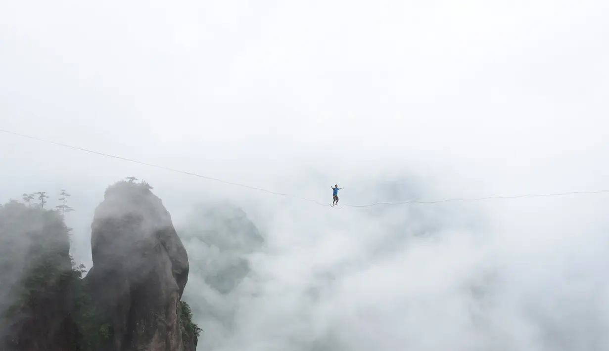 Seorang peserta berjalan diatas tali untuk menyebrangi tebing tinggi di Provinsi Zhejiang , China , 7 Mei 2016. Hanya dengan seutas tali di kaki, mereka berlomba untuk menyebrangi tebing tersebut. (China Daily /REUTERS)