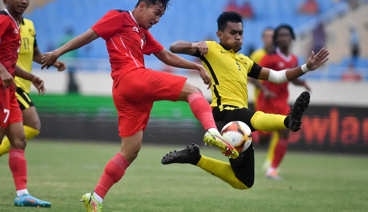 Gelandang Timnas Indonesia U-23, Witan Sulaeman berebut bola dengan bek Malaysia, Harith Haiqal bin Adam Afkar dalam pertandingan perebutan medali perunggu SEA Games 2021 di Stadion My Dinh, Minggu (22/5/2022). Indonesia ditahan imbang 1-1 dan menang 4-3 di adu penalti. (AFP/Ye Aung Thu)