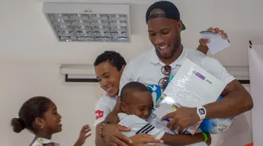 Mantan pemain sepak bola Didier Drogba memeluk anak-anak saat acara amal organisasi internasional Peace and Sport, di Cartagena, Kolombia (19/3). Didier Drogba merupakan pesebak bola dunia dari Pantai Gading. (Cesar Carrion/Colombian Presidency/AFP)