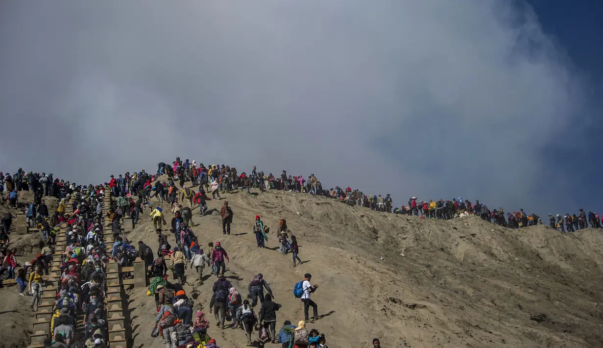 Wisatawan dan anggota suku Tengger mendaki Gunung Bromo saat Festival Yadnya Kasada di Probolinggo, Jawa Timur (10/7). Warga Tengger melakukan ritual lempar hasil bumi sebagai wujud syukur pada Sang Hyang Widi. (AFP Photo/Juni Kriswanto)