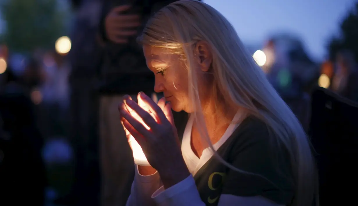 Seorang wanita membawa lilin saat melakukan aksi simpatik mengenang korban penembakan di Kampus Umpqua Community College di Roseburg, Sabtu (3/10/2015). Setidaknya 15 orang tewas dalam peristiwa tersebut. (REUTERS / Lucy Nicholson)
