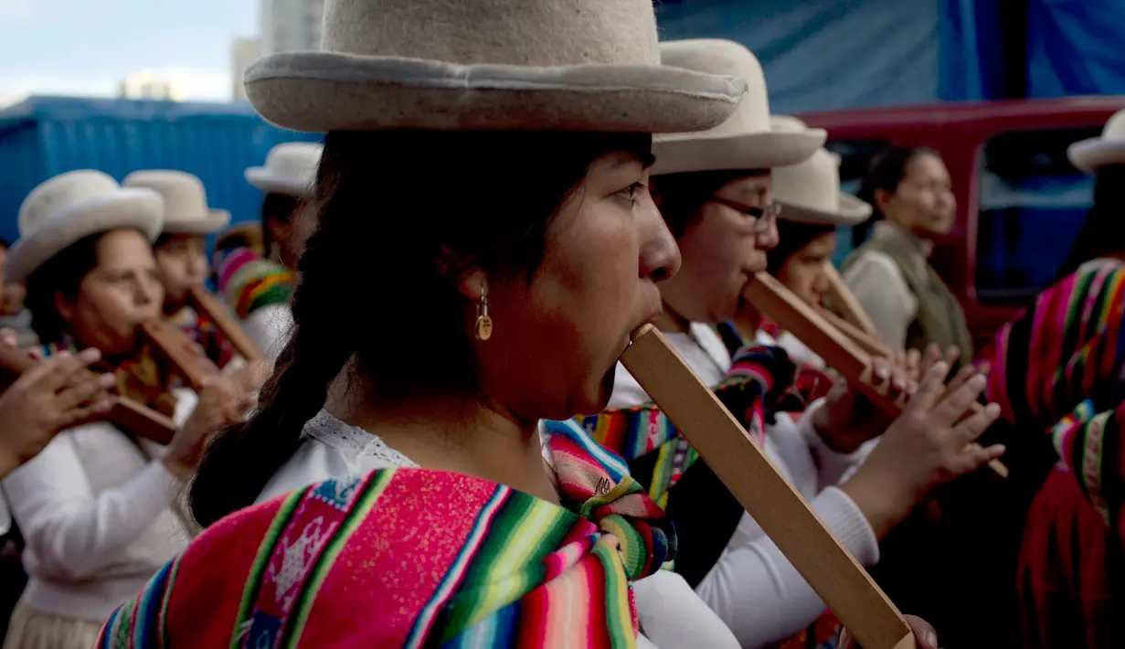 Pemain musik wanita bermain seruling saat prosesi arak-arakan patung dewa Ekeko di La Paz, Bolivia (23/1). Alasita ini awalanya sebuah pameran dimana orang pribumi bertukar miniatur dan beberapa barang kebutuhan penting lainnya. (AP Photo / Juan Karita)