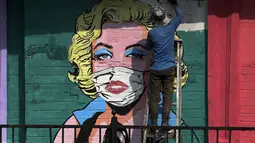 Seniman melukis mural untuk menyebarkan kesadaran akan pencegahan virus corona di Mumbai, India (26/3/2021). Kementerian Kesehatan melaporkan 43.846 kasus baru dalam 24 jam terakhir, peningkatan satu hari terburuk sejak pertengahan November. (AP Photo/Rajanish Kakade)