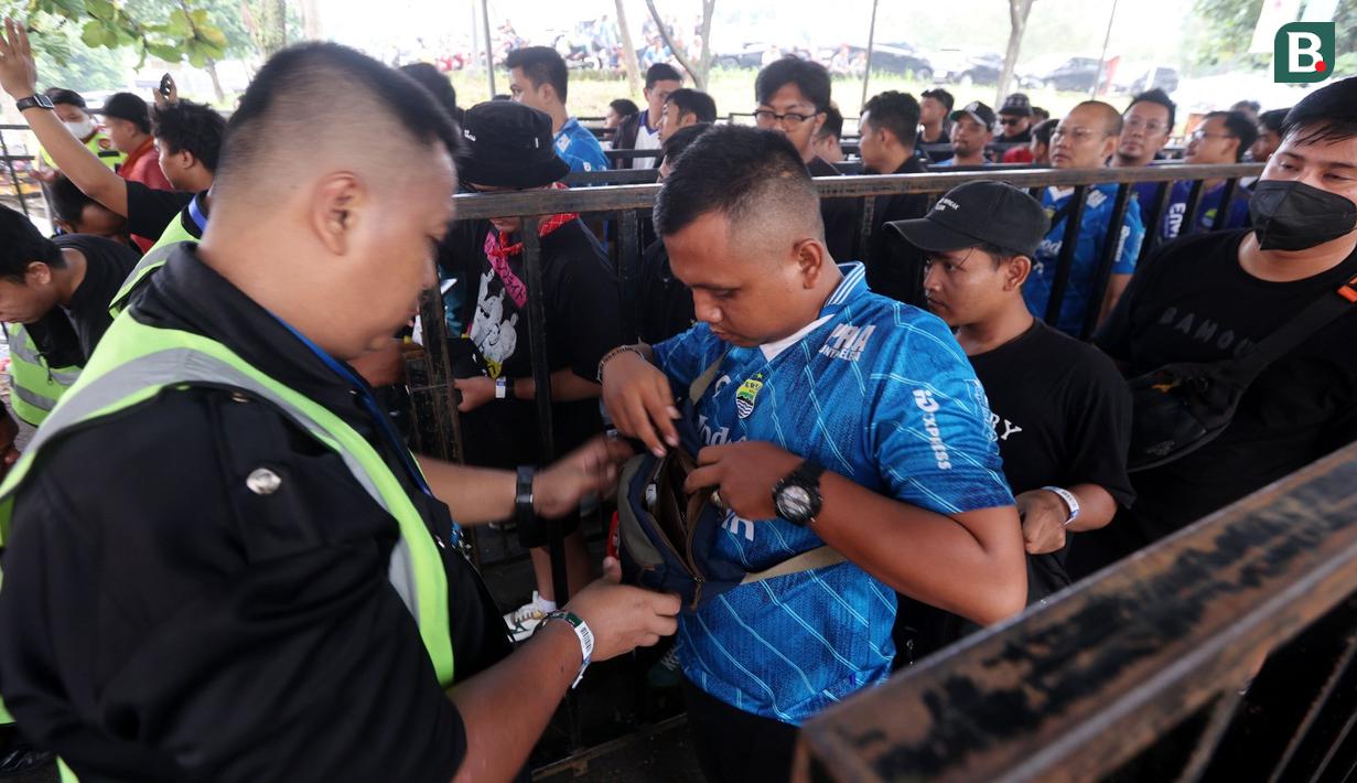 Petugas keamanan mememeriksa tas dari seorang pendukung Persib Bandung sebelum laga leg 1 final Championship Series BRI Liga 1 2023/2024 melawan Madura United di Stadion Si Jalak Harupat, Bandung, Minggu (26/05/2024). (Bola.com/Muhammad Iqbal Ichsan)