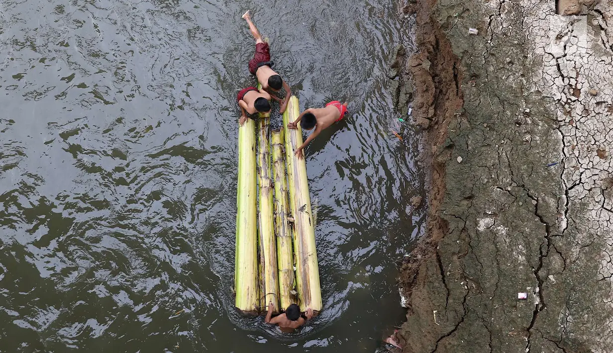 Anak-anak berenang menggunakan batang pohon pisang di bantaran Sungai Ciliwung, Jakarta, Selasa (15/5). Kurangnya pengawasan menyebabkan anak-anak tersebut bermain tidak pada tempatnya. (Liputan6.com/Immanuel Antonius)