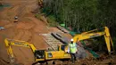 Para pekerja berjalan di dekat alat berat di lokasi pembangunan ibu kota baru di Penajam Paser Utara, Kalimantan Timur, Indonesia, Rabu, 8 Maret 2023. Pemerintah menjanjikan "kota hutan lestari" yang menempatkan lingkungan sebagai jantung pembangunan dan bertujuan untuk menjadi netral karbon pada tahun 2045. (AP Photo/Achmad Ibrahim)