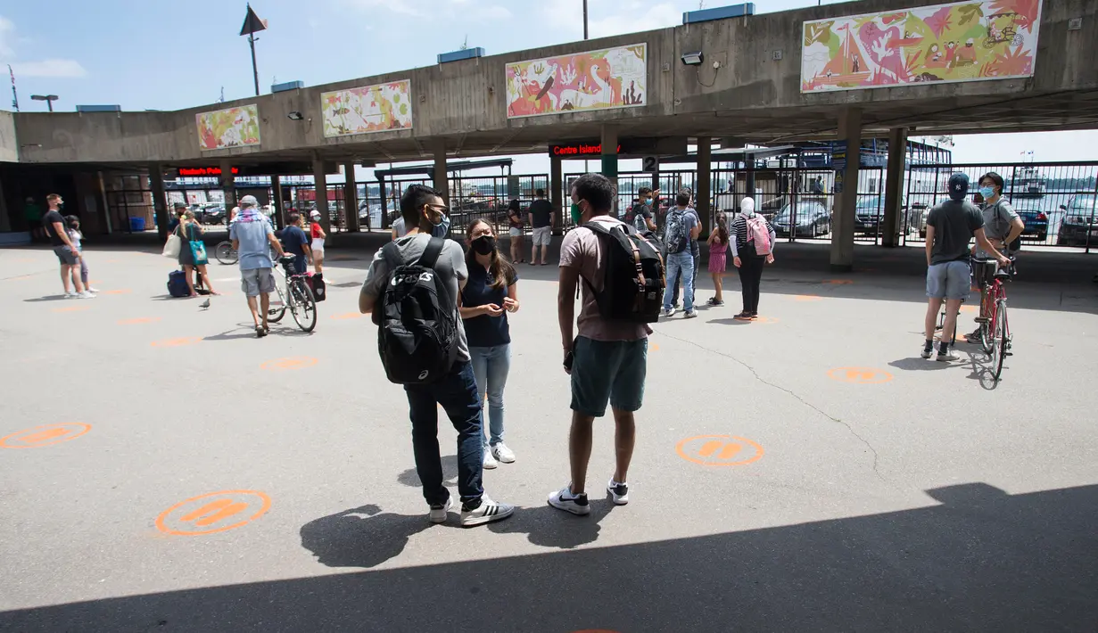 Para penumpang yang mengenakan masker menunggu untuk menaiki kapal feri dengan menjaga jarak fisik di Terminal Feri Jack Layton di Toronto, Kanada (27/6/2020). (Xinhua/Zou Zheng)