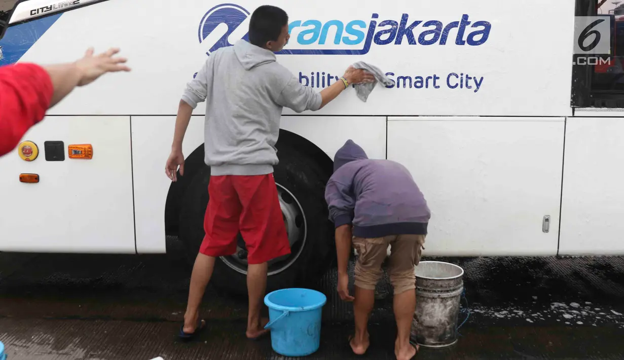 Suporter Persija, Jakmania, mencuci bus transjakarta di kantor PT Transjakarta, Jakarta, Kamis (13/12). Hal tersebut bentuk tanggung jawab atas aksi vandalisme oknum suporter saat Persija meraih Juara Liga 1 2018. (Liputan6.com/Immanuel Antonius)