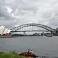 Dua pelari beristirahat di Kursi Nyonya Macquarie yang menghadap ke Opera House dan Harbour Bridge di Sydney, Rabu (30/12/2020). Klaster baru virus korona (Covid-19) muncul di kota Sydney, New South Wales, Australia, menjelang pergantian tahun. (Saeed KHAN / AFP)