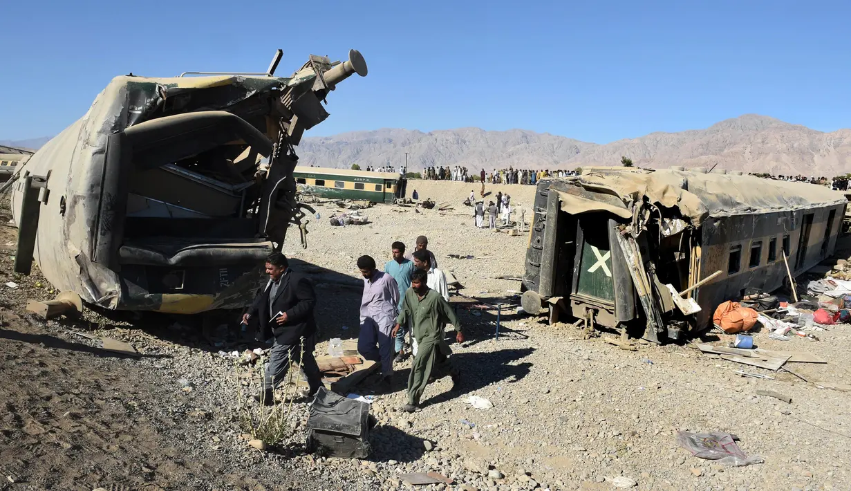 Penumpang melewati gerbong kereta yang rusak akibat tergelincir dari rel di daerah pegunungan Bolan dekat Quetta dalam perjalanan ke Rawalpindi, Pakistan, Selasa (17/11). Sedikitnya 12 orang tewas dan ratusan terluka. (AFP PHOTO/BANARAS KHAN)