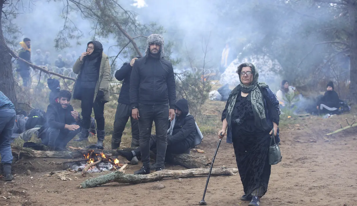 Para migran dari Timur Tengah dan tempat lain beristirahat dan menghangatkan diri saat berkumpul di perbatasan Belarusia-Polandia dekat Grodno, Belarus, Senin (8/11/2021). (Leonid Shcheglov/BelTA via AP)