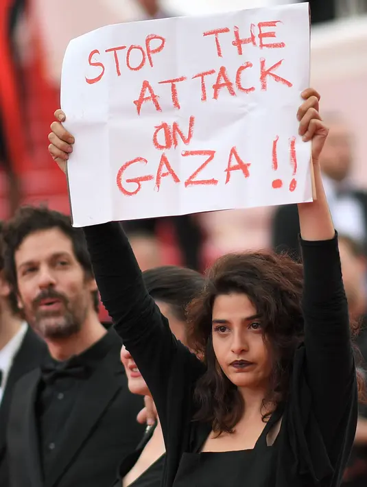 Aktris Manal Issa memegang poster bertuliskan "Hentikan Serangan di Gaza" saat menghadiri pemutaran film "Solo: A Star Wars Story" dalam Festival Film Cannes ke-71 di Cannes, Prancis (15/5). (AFP/Loic Venance)