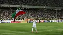 Pemain timnas Iran, Ramin Rezaeian mengibarkan bendera nasional usai mengalahkan Uzbekistan pada kualifikasi Grup A zona Asia, Senin (12/6). Iran menjadi negara ketiga yang memastikan diri tampil ke putaran final Piala Dunia 2018. (AP Photo/Vahid Salemi)