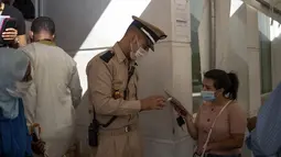 Petugas polisi memeriksa paspor vaksin seorang wanita sebelum diizinkan memasuki kantor pemerintah, di Rabat, Kamis (21/10/2021). Maroko mewajibkan paspor vaksin untuk mengakses kantor pemerintah, mal, pusat kebugaran dan area publik lain untuk mendorong kampanye vaksinasi (AP Photo/Mosa'ab Elshamy)