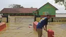 Seorang anak berada di depan sekolah yang terendam banjir di Desa Sukalaksana Kabupaten Bekasi, Jawa Barat, Senin (22/02/2021). Banjir tersebut akibat luapan sungai Citarum yang tanggulnya jebol. (Liputan6.com/Herman Zakharia)