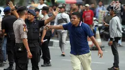 Massa membawa batu saat demonstrasi yang berujung ricuh di depan gedung KPK, Kuningan, Jakarta, Jumat (13/9/2019). Sempat terjadi baku hantam dalam demo itu saat massa aksi pendukung revisi Undang-Undang KPK mencoba merangsek untuk mencopot kain hitam yang menutupi logo KPK. (Liputan6.com/HO/Andri)