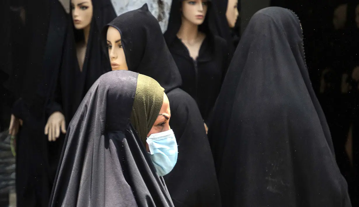 Seorang wanita berjalan melewati pasar pakaian di Kota Basra, Irak, Kamis (21/5/2020). Jelang Idul Fitri, pemerintah Irak melonggarkan lockdown karena pandemi virus corona COVID-19. (Hussein FALEH/AFP)