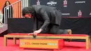 Aktor Keanu Reeves membubuhkan tanda tangan dalam upacara pembuatan cetakan tangan dan kaki di TCL Chinese Theatre, Los Angeles, Selasa (14/5/2019). Aktor 54 tahun itu mendapat penghargaan membuat cetakan tangan dan kaki untuk merayakan keberhasilan karirnya dalam film. (Willy Sanjuan/Invision/AP)