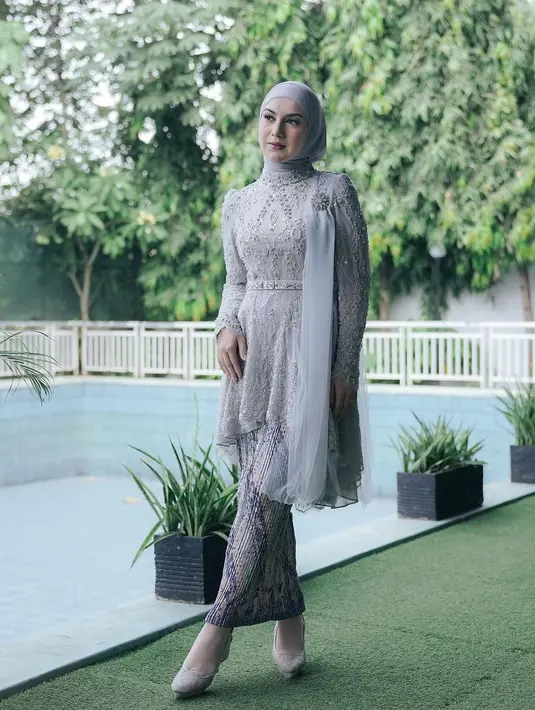 Hijab lilit juga dikenakan Irish Bella saat mengenakan kebaya kurung asimetris abu-abu. Aksen selendang di bahu kiri bikin tambah elegan [@_irishbella_]