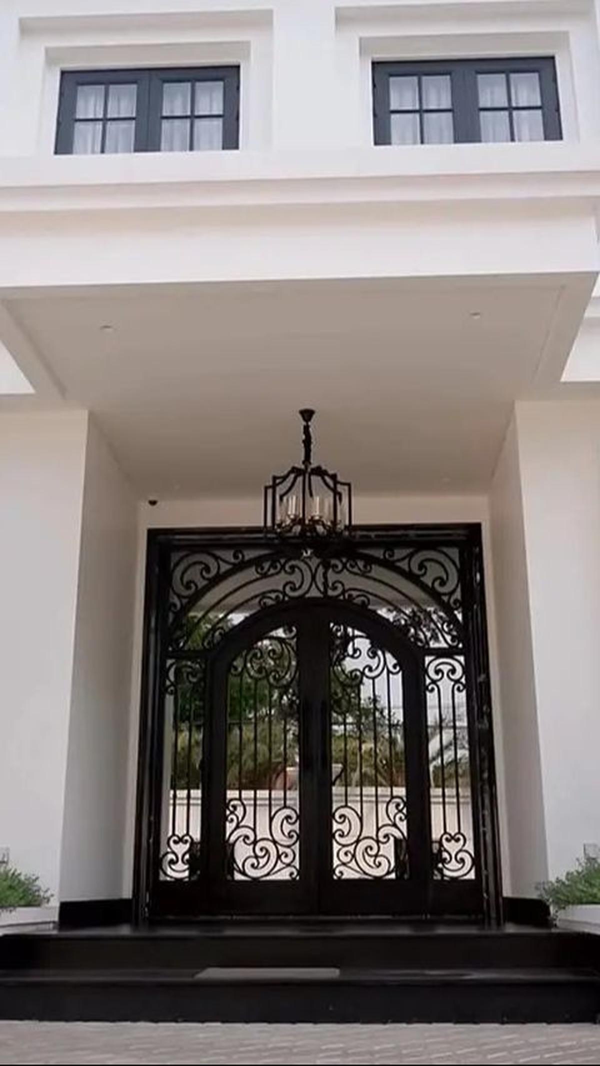 Rumah ini dua lantai, pintu masuk estetik dengan kaca satu arah dan model teralis hitam yang elegan.